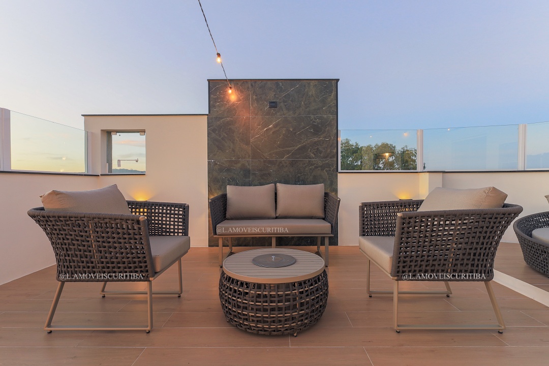Lounge do rooftop com poltronas e mesa de centro ao entardecer