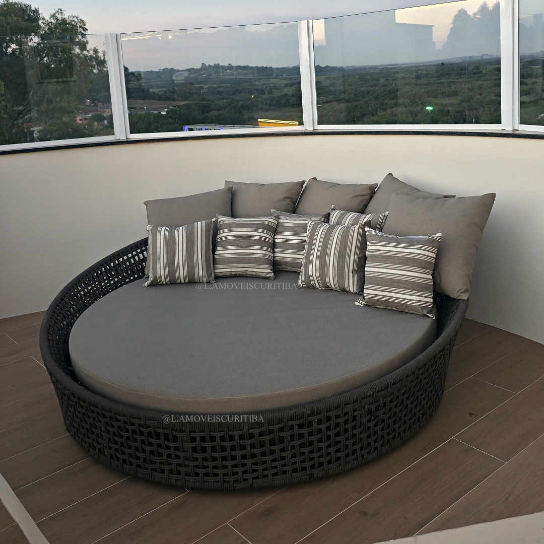 Chaise redonda com almofadas listradas em varanda envidraçada