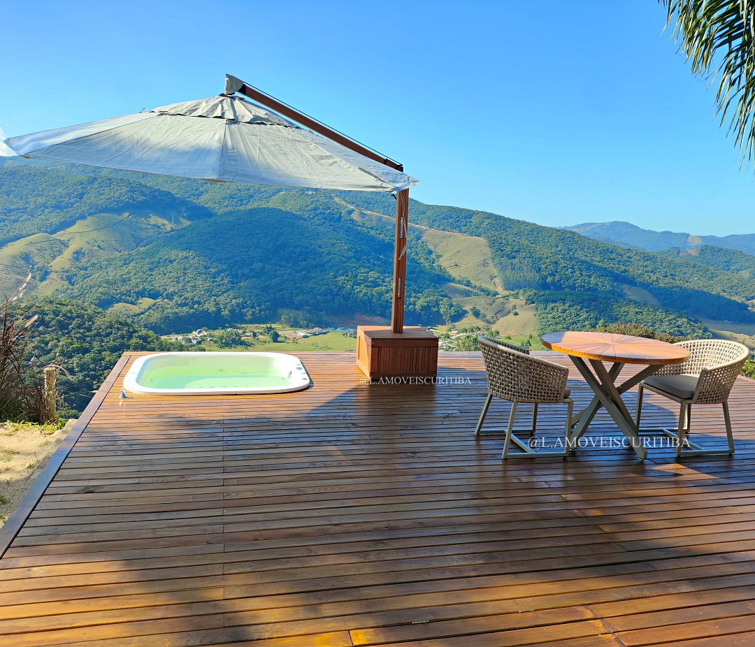 Deck de madeira com ofurô e mesa outdoor diante das montanhas