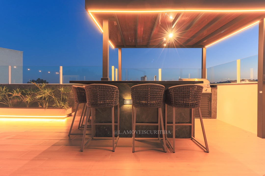 Banquetas altas na bancada gourmet sob pergolado iluminado