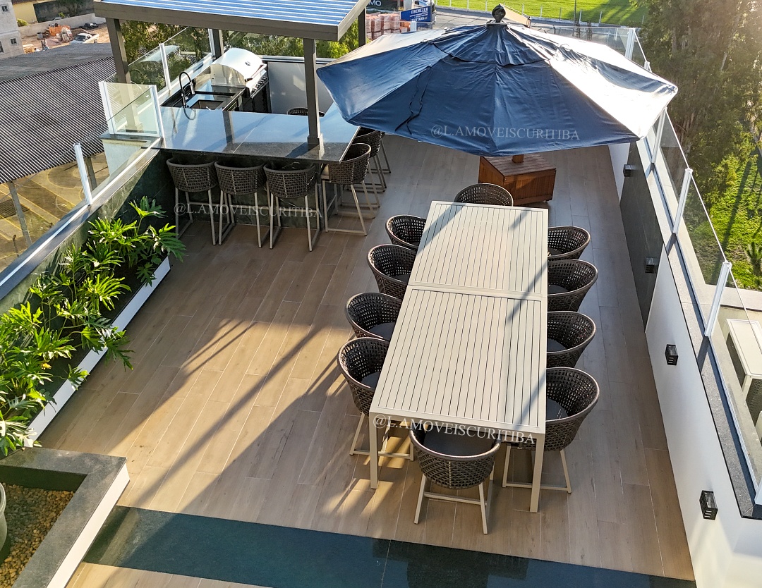 Vista aérea do rooftop com mesa de jantar para dez lugares e churrasqueira